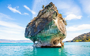 rock monolith on body of water HD wallpaper