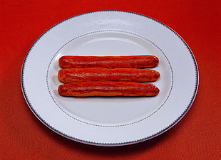 three hotdogs in white ceramic plate
