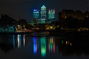 reflection of high-rise buildings on calm body of water during nighttime, canary wharf