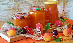 three orange glass jars on top of brown wooden surface