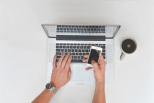 person holding iPhone on top of MacBook