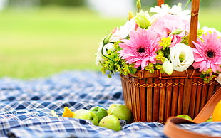 selective focus photography of picnic basket full of flowers