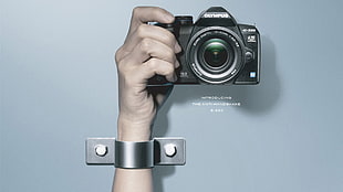 person holding black Olympus camera HD wallpaper