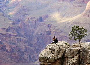 photography of person sitting on clif