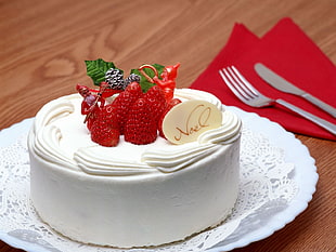white cake with icing and strawberry toppings