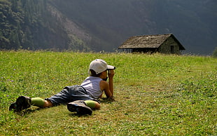 boy wearing a gray tank top and short laying on green grass field during daytime
