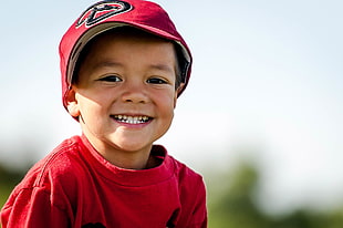 selective focus photography of boy wearing red cap