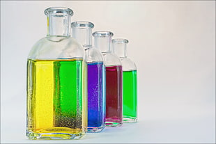 four clear glass bottles with colored liquids