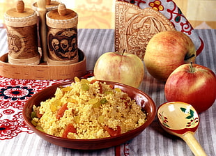 photo of cooked rice in red bowl beside three apples