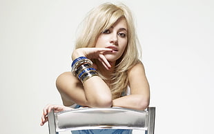 blonde-haired woman sitting on steel chair wearing bangles