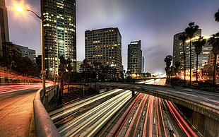 Time-lapse photography of roads between high-rise building during nighttime