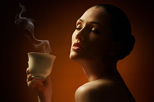 woman holding white ceramic cup