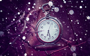 silver-colored pocket watch with snow falling