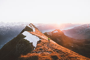 person walking towards mountain peak during golden hour