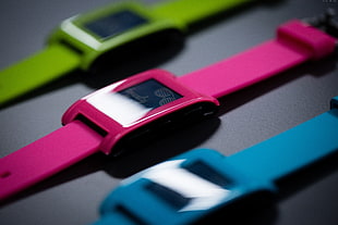shallow focus photo of green, pink, and blue smartwatches