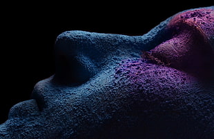 person's face with blue and purple powder in dark room