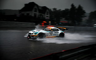 white, green, and orange BMW rally car running on wet road
