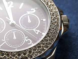 diamond embellished round black chronograph watch on blue surface