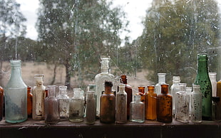 assorted glass bottle beside window