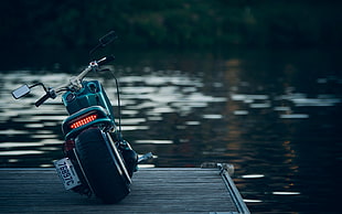 black cruiser motorcycle on brown wooden dock in front of body of water