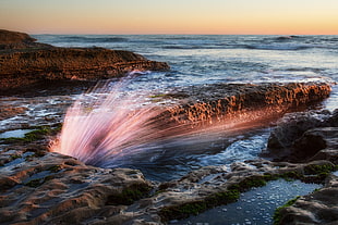 time lapse photo of light in rock formation at the sea