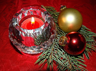 red lighted votive candle with two brown and red christmas baubles HD wallpaper