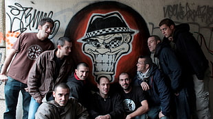 photo of nine man beside beige skull painted wall