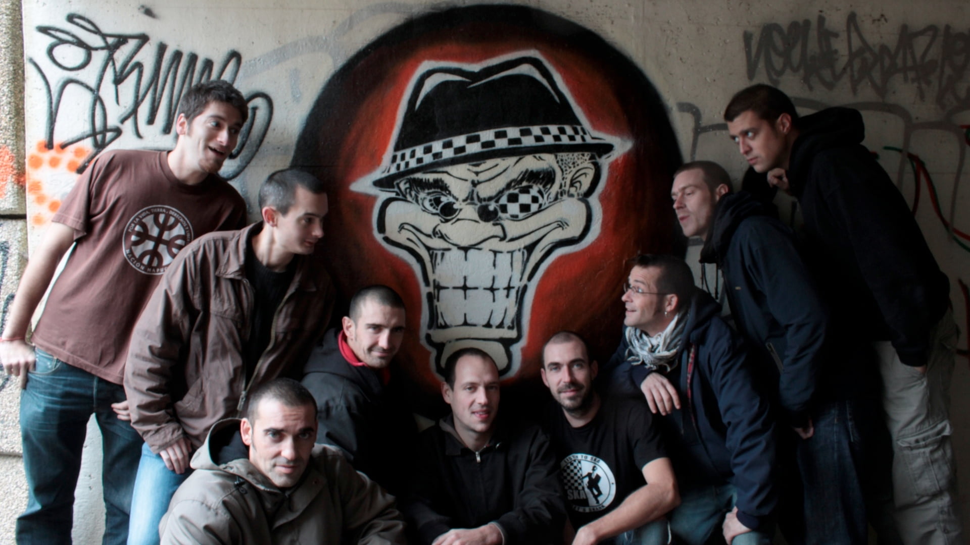 photo of nine man beside beige skull painted wall