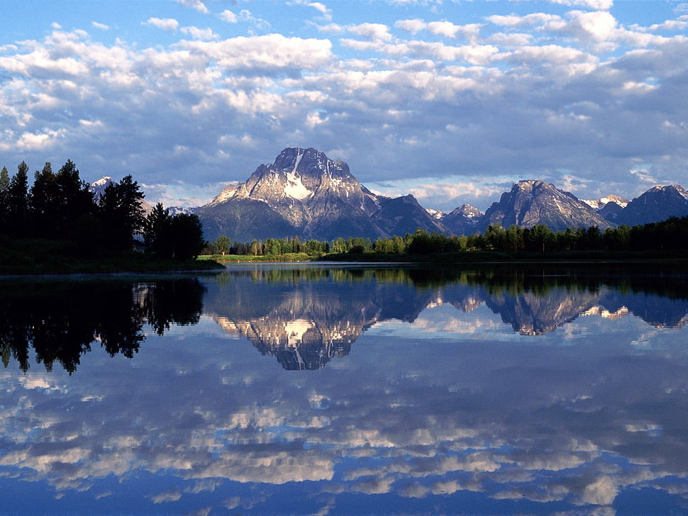 mountain in distance with body of water refection of mountain under cloudy sky at daytime HD wallpaper