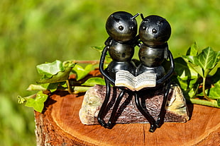 two gray ant figurines reading books