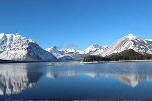 snow covered mountains near body of water during daytime, upper kananaskis lake, canada
