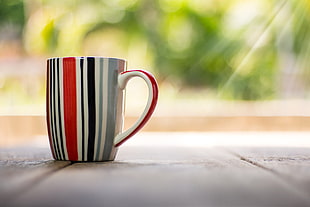 white, black and red ceramic coffee cup during daytime
