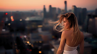 woman wearing white dress standing near edge over viewing highrise buildings