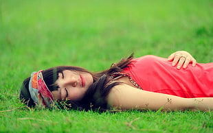 woman wearing pink sleeveless top lying on green grass during daytime