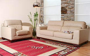 closeup photo of beige mid-century modern 2-piece sofa near beige wall and red area rug
