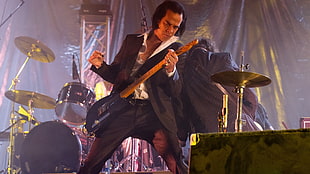 man in black suit playing black electric guitar