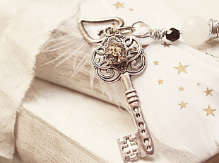 silver key pendant on top of white textile