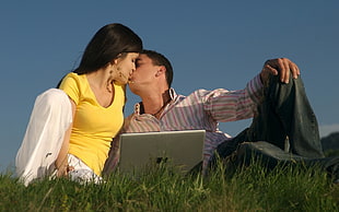 man and woman kissing in front of MacBook