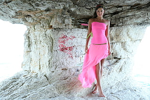 woman wearing pink tube dress standing under rock formation