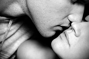 grayscale photo of man and woman almost kissing