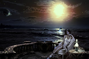 woman sitting on gray chair near seashore during night time