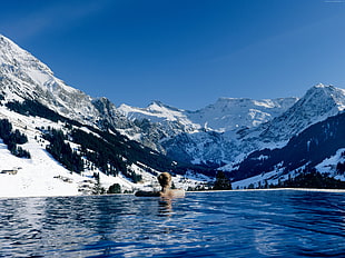 woman on swimming pool in front of snow covered mountain