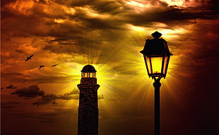 photography of black light post and brown light house during sunset