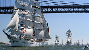 white sailing ships crossing bridge