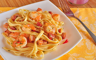 pasta with shrimp on square white ceramic plate beside stainless steel fork
