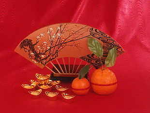 two orange fruits and gold-colored charm boats