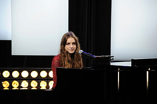 woman wearing red floral long sleeve shirt while playing grand piano