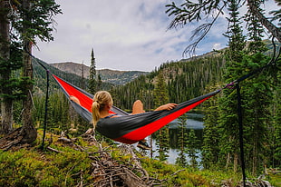 woman in blonde hair lying on red and black hammock during daytime