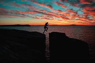 silhouette of man jumping over cliff HD wallpaper