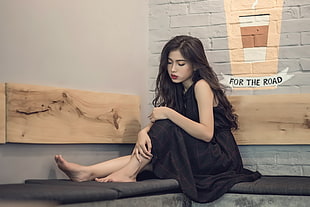 woman wearing black sleeveless dress sitting on black chair